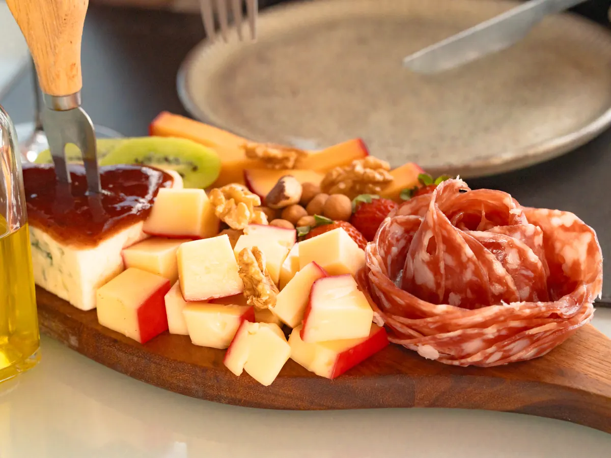 Tábua de frios com queijos, salame, nozes, frutas e geleia